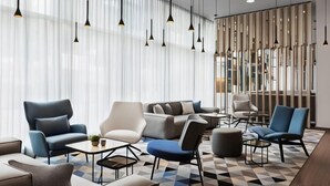 A modern hotel lobby with a geometric patterned floor, contemporary furniture, and pendant lighting. - Courtyard by Marriott Munich City East (Munich)