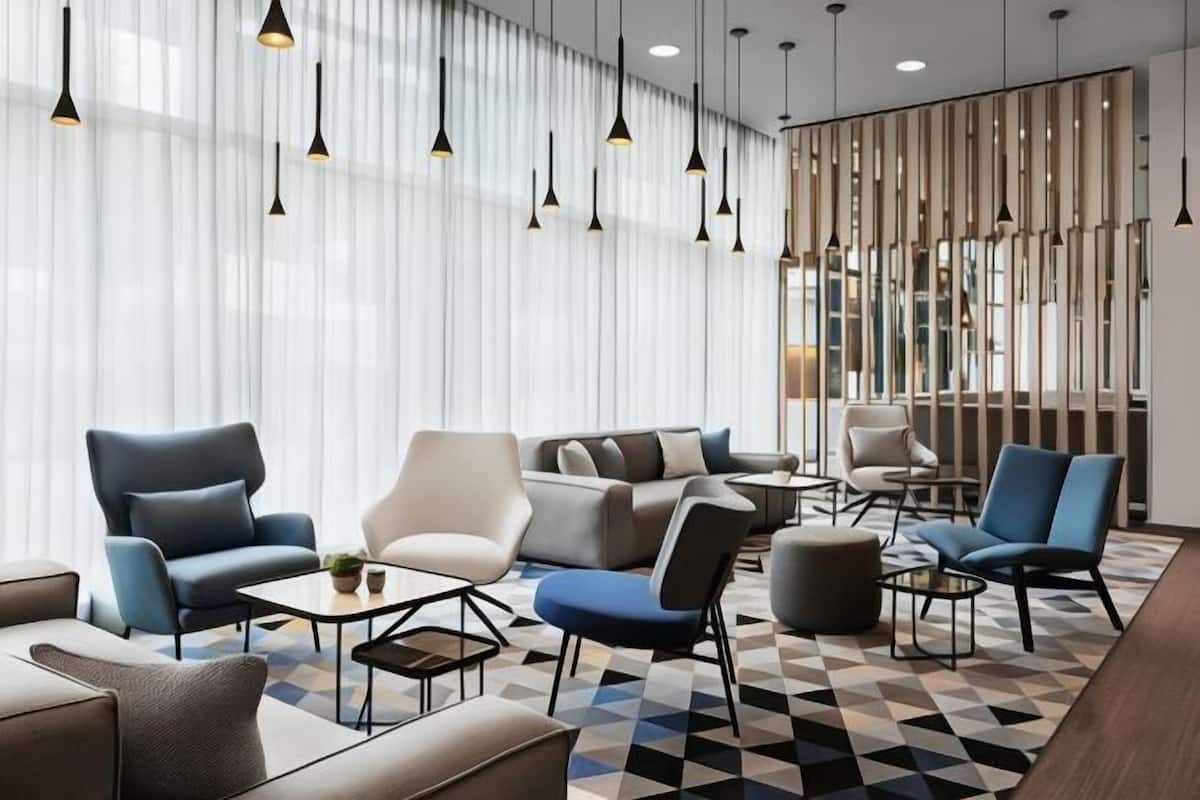 A modern hotel lobby with a geometric patterned floor, contemporary furniture, and pendant lighting.