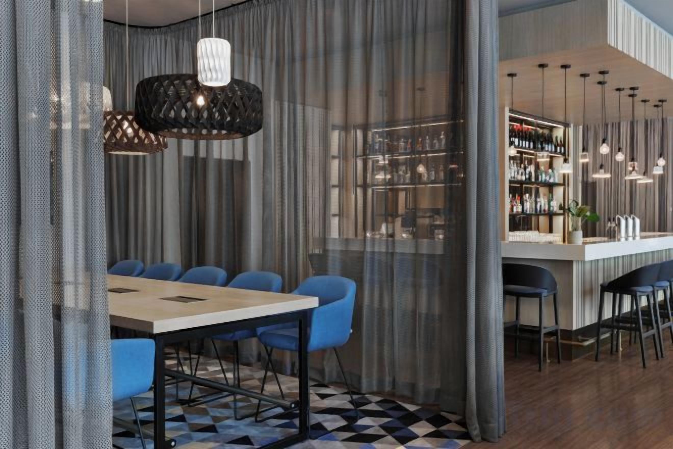 A modern bar area with a checkered floor, bar stools, and hanging pendant lights.