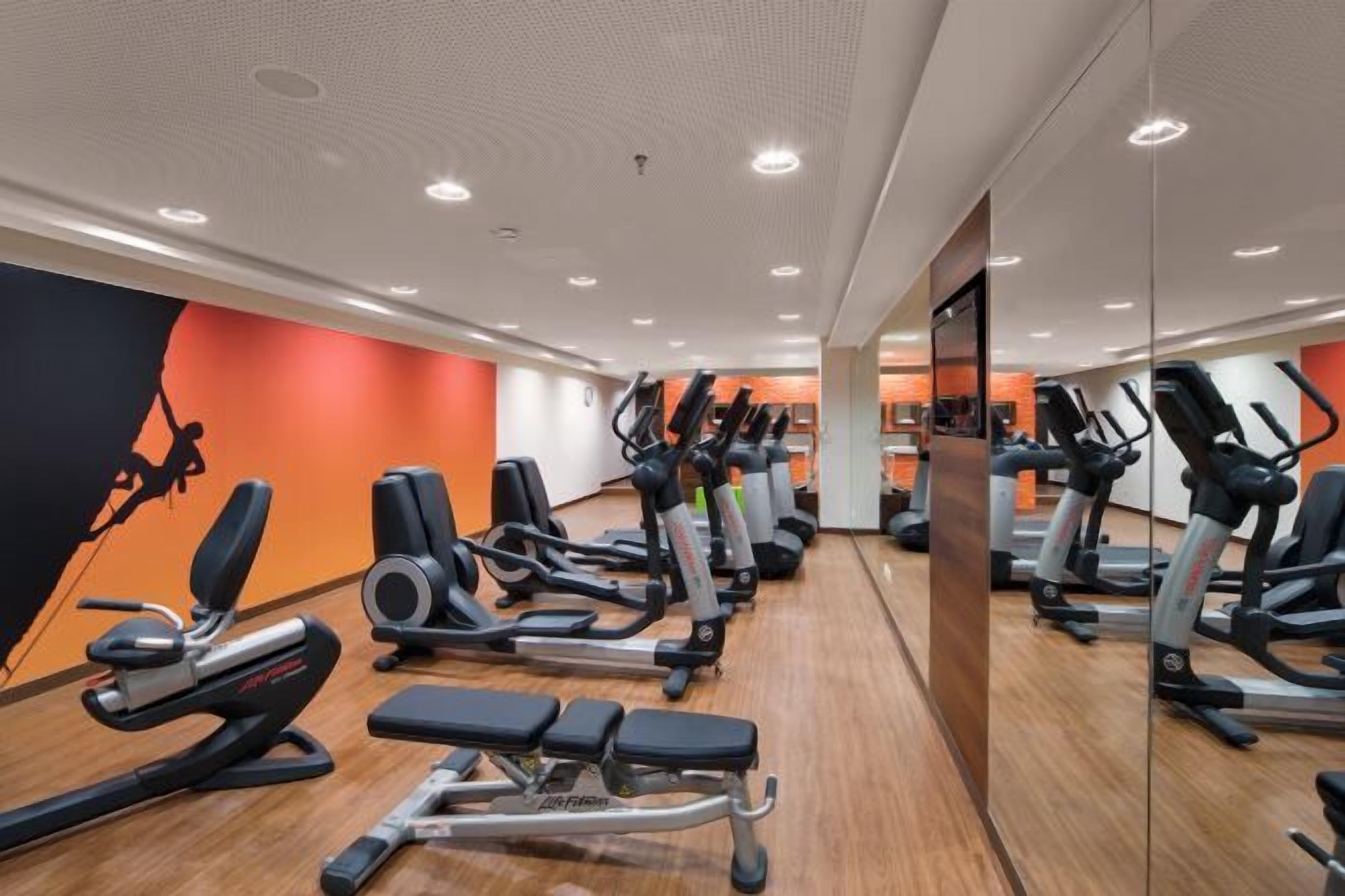 A gym with various exercise equipment, including treadmills and weight machines, arranged in rows.