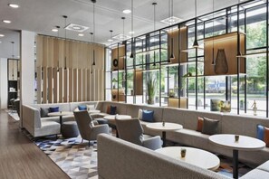 A modern lounge area with sofas, round tables, and pendant lighting. - Courtyard by Marriott Munich City East (Munich)