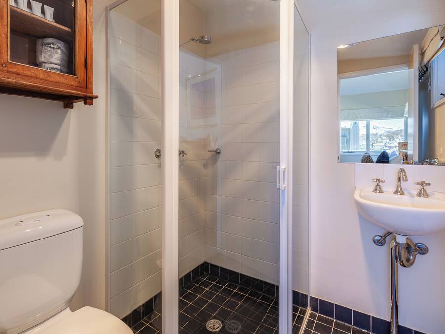 Un baño con inodoro, ducha con puerta de cristal y lavabo con espejo.