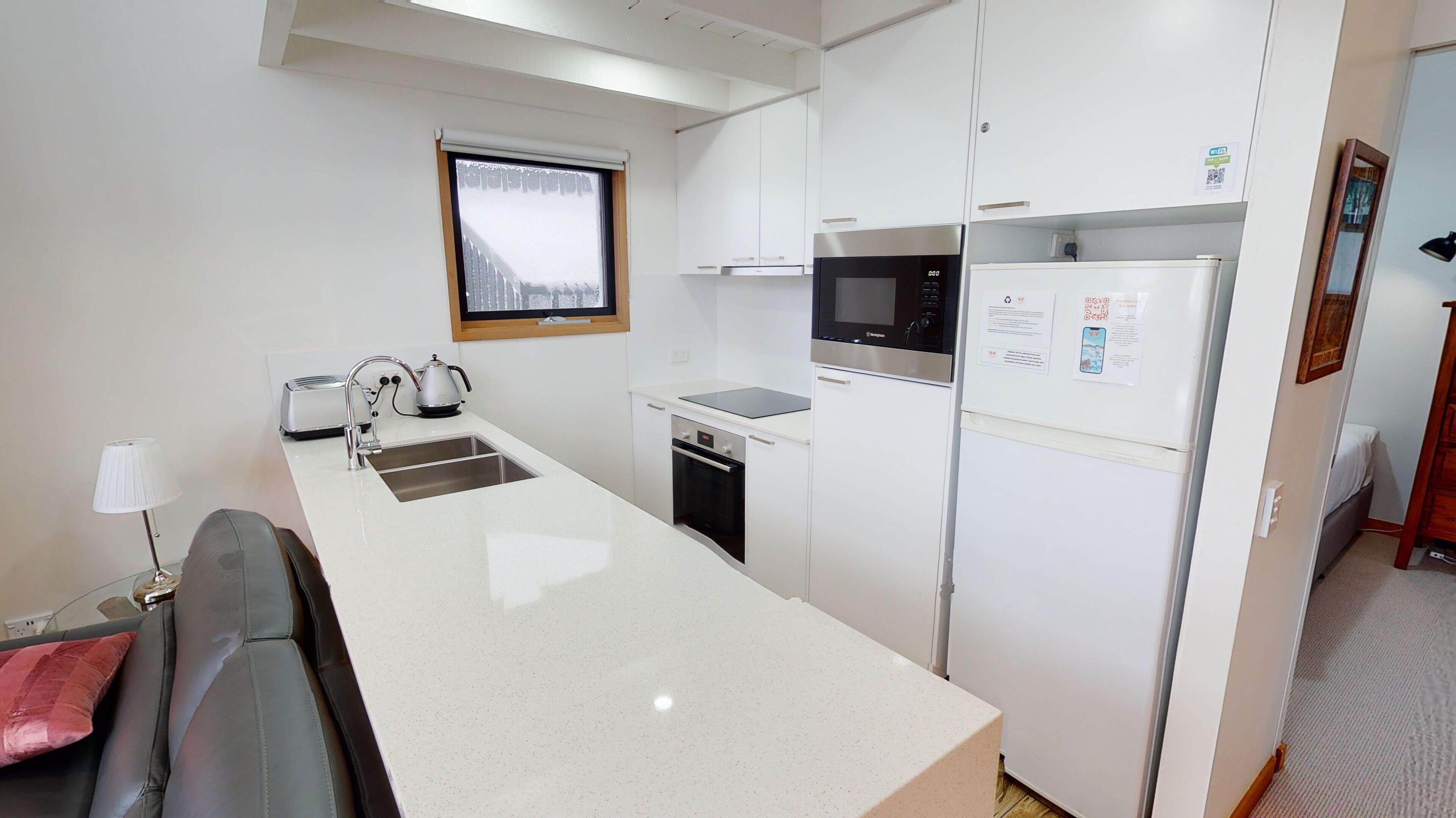 Cocina compacta con encimera, pileta, estufa, microondas y refrigerador.