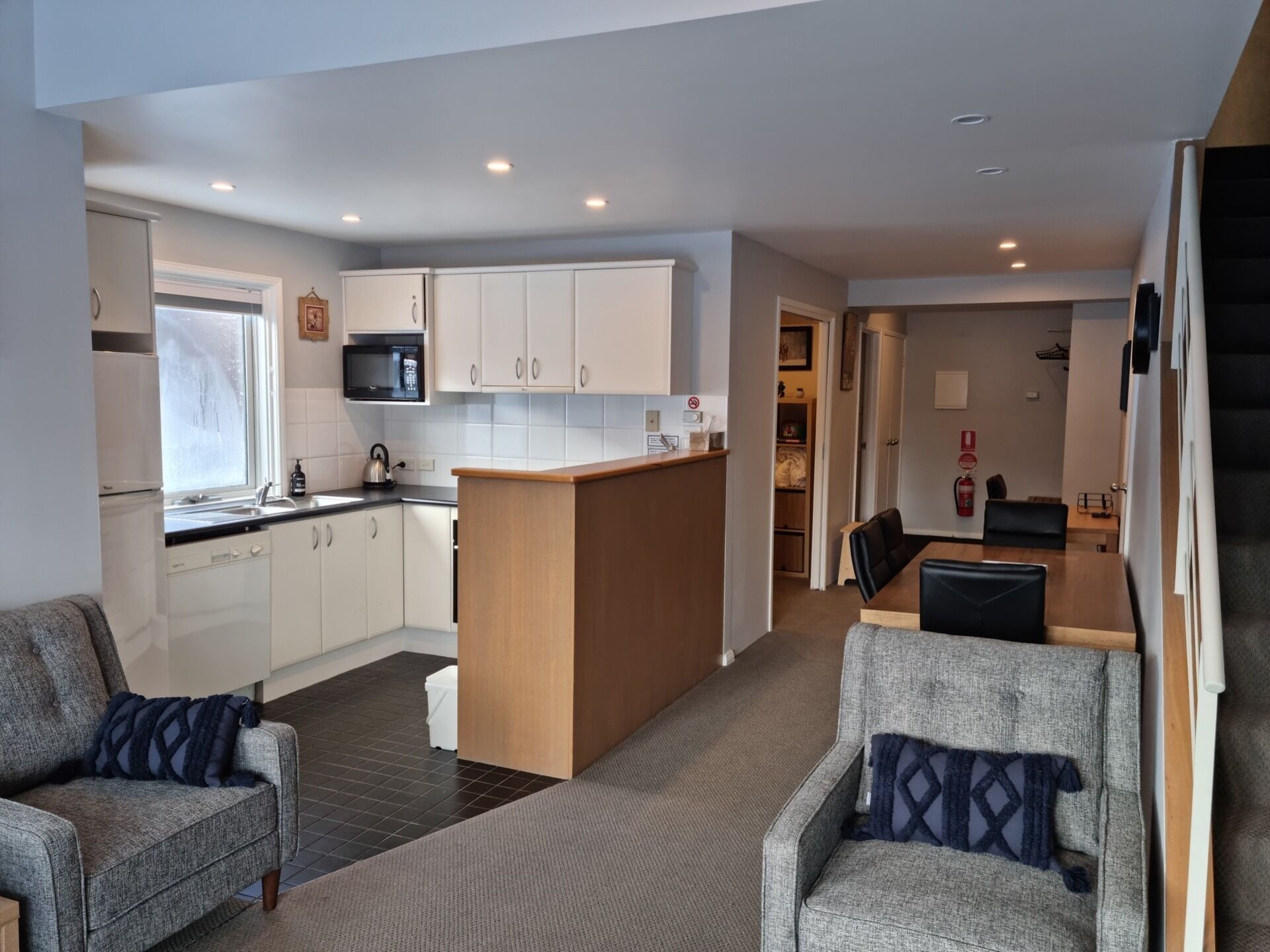 A modern kitchen with white cabinets, a microwave, and a dining area with a table and chairs.