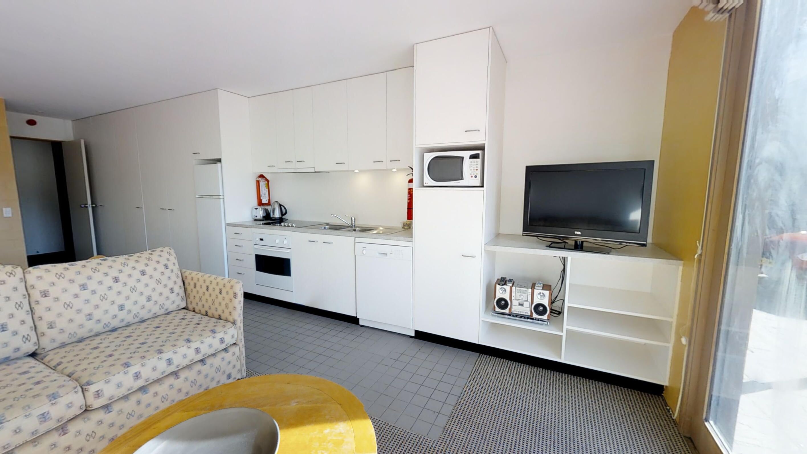 Un espacio habitable compacto con kitchenette, un sofá, un televisor y una pequeña zona de estar.