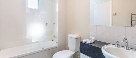 A modern bathroom with a bathtub, toilet, and sink.