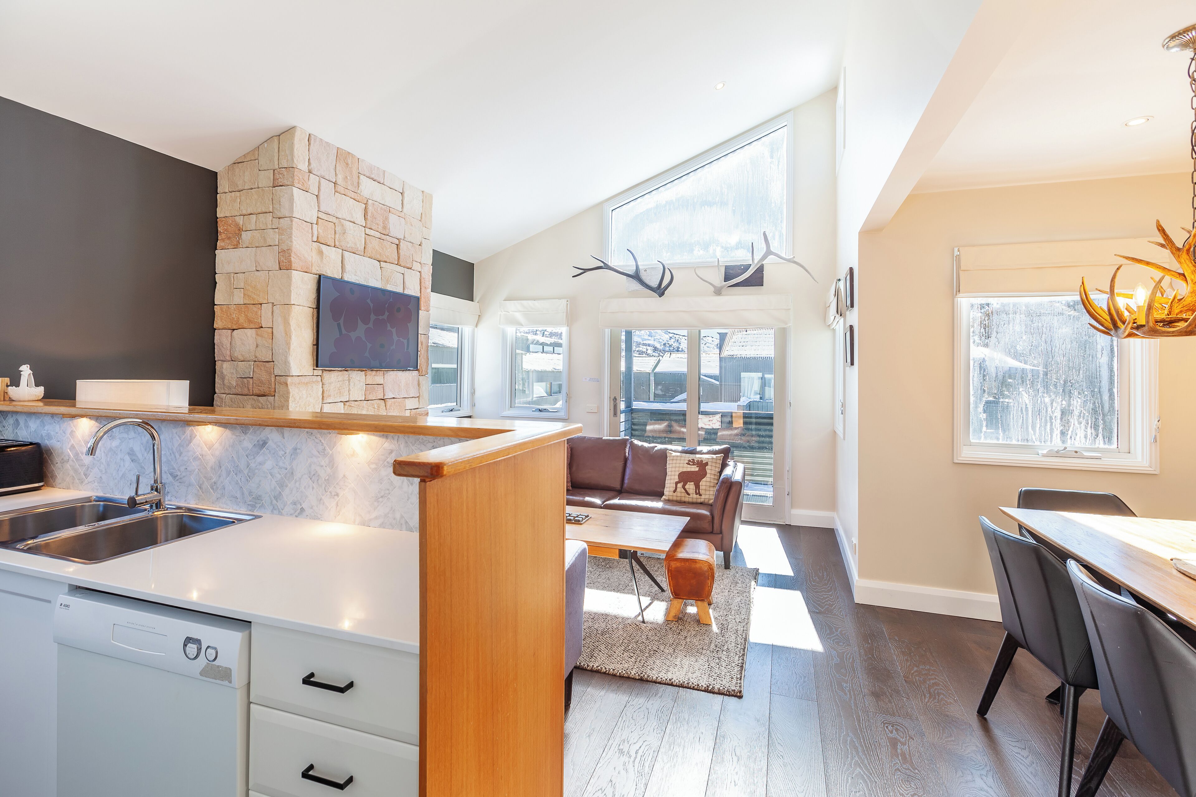 A modern kitchen with a stone accent wall, a dining area with a view, and a living space with a fireplace.