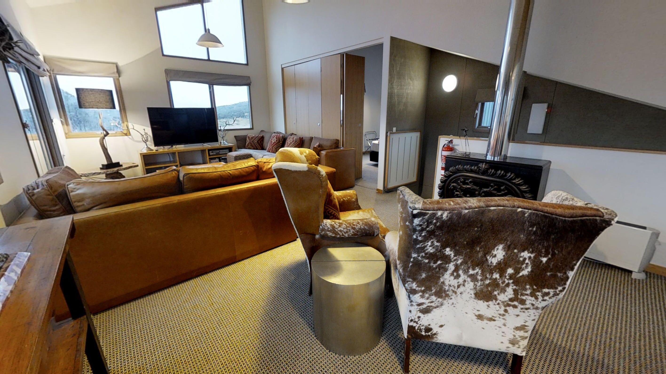 Una sala moderna con un sofá, sillones, televisor y chimenea.