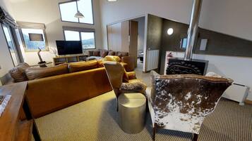 Una sala moderna con un sofá, sillones, televisor y chimenea.