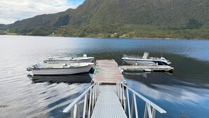 Un quai avec des bateaux, une jetée en bois et un paysage montagneux en arrière-plan.