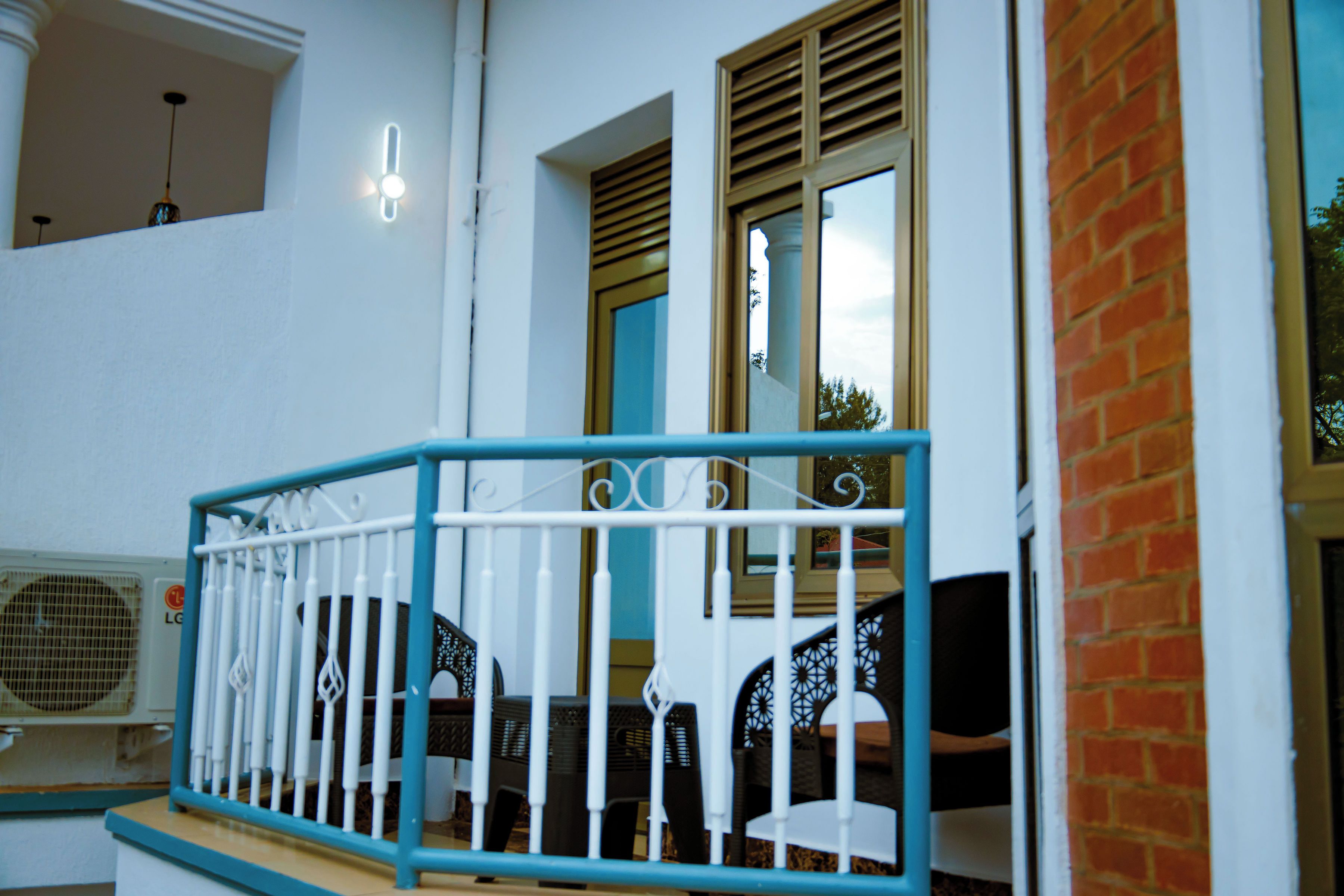 A balcony with a white railing, a window with blinds, and a view of the sky.