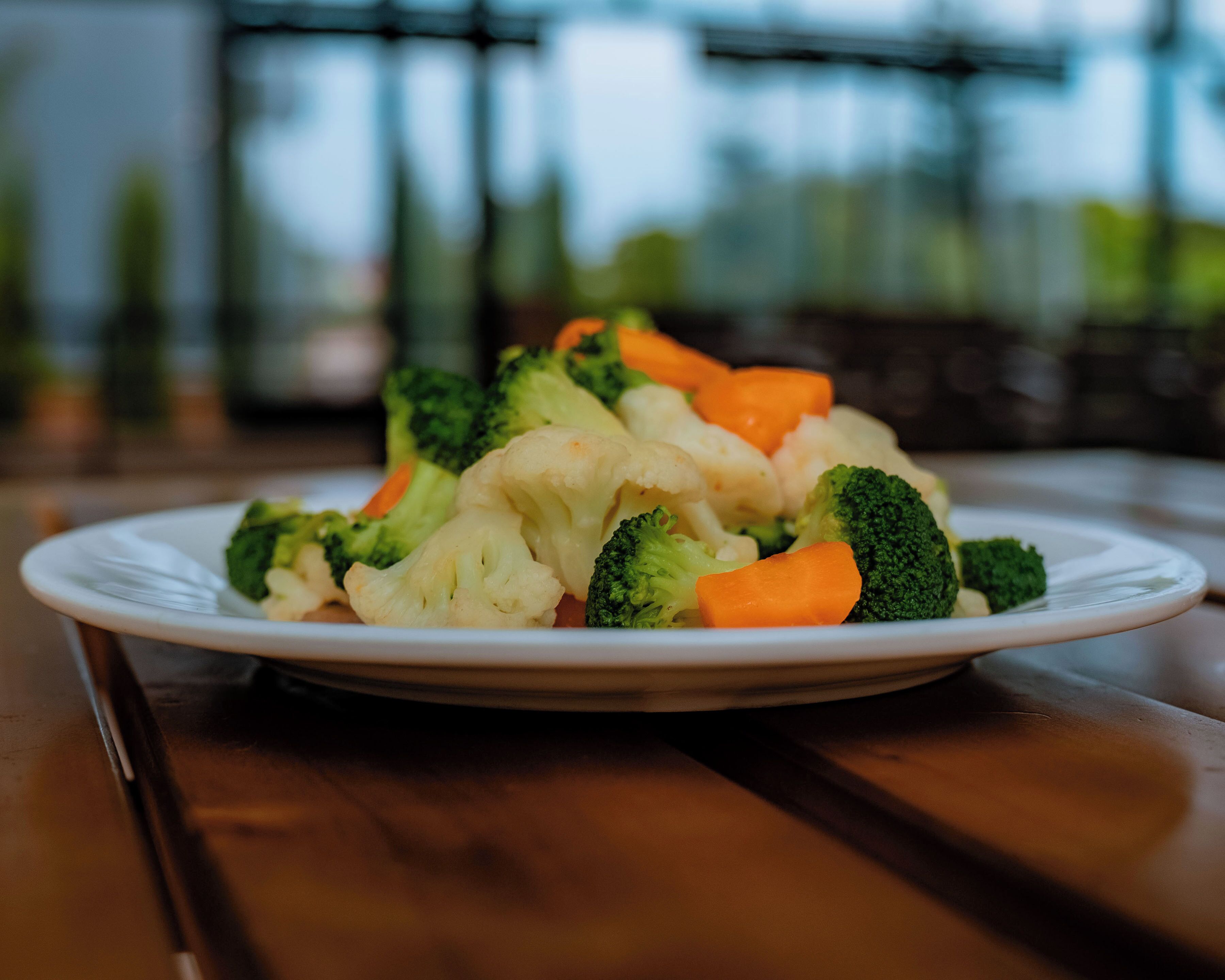 A plate of mixed vegetables on a wooden table.