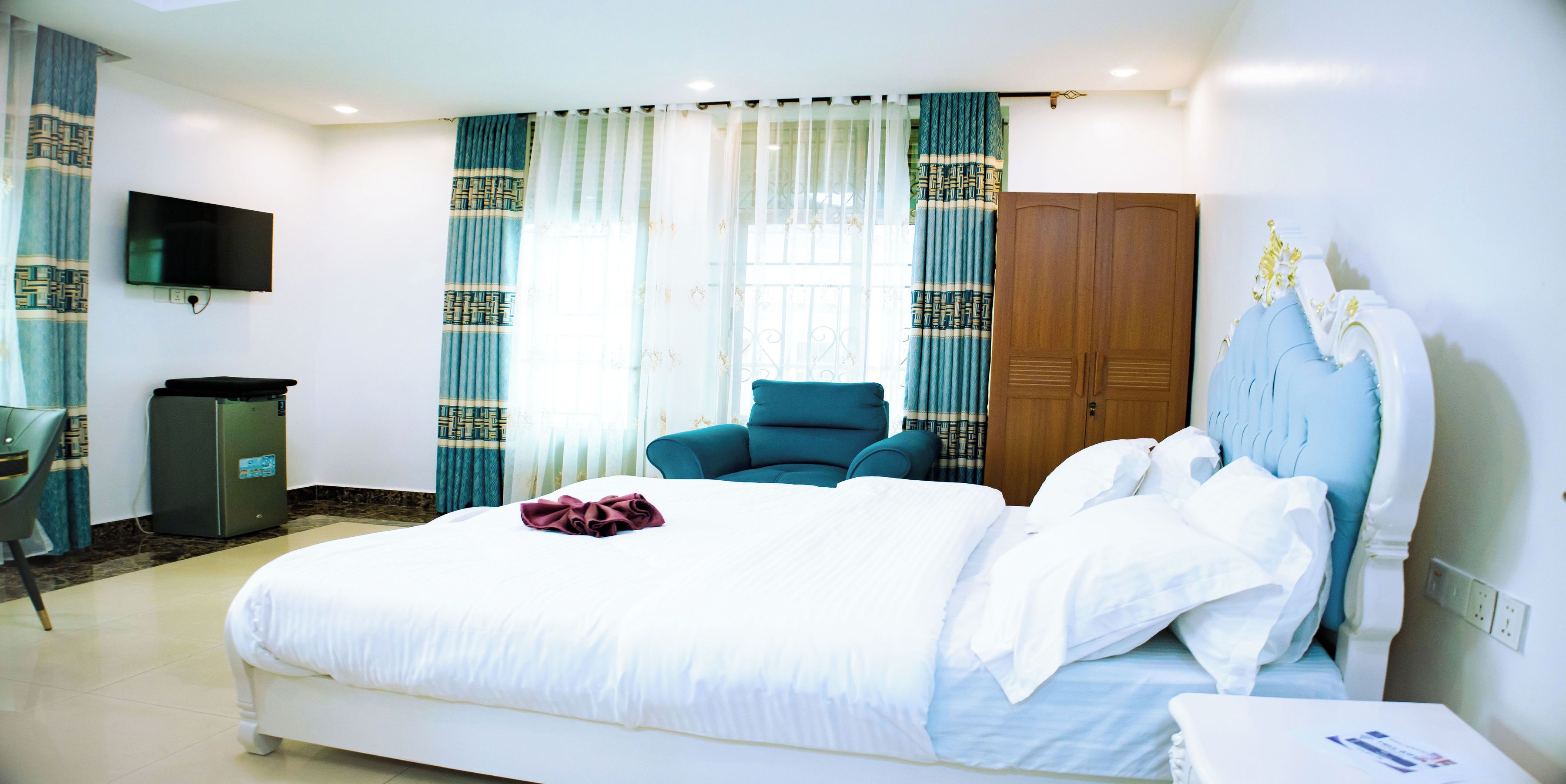 Una habitación de hotel con una cama, una silla, un televisor y un armario.