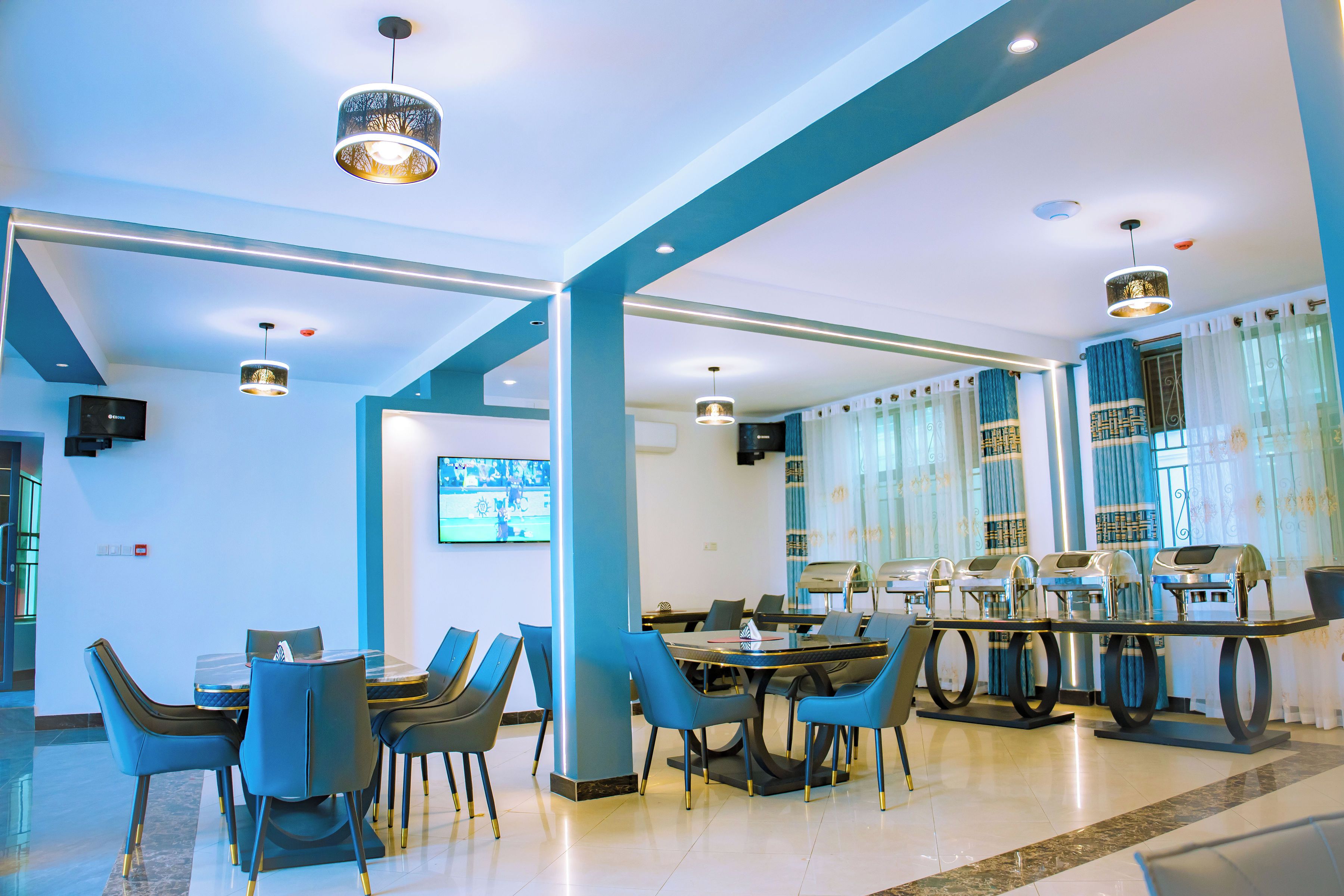 Un moderno vestíbulo de hotel con zona de estar, una pantalla de televisión y una estación de café.