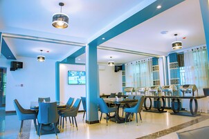 Un moderno vestíbulo de hotel con zona de estar, una pantalla de televisión y una estación de café.