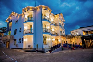 Un hotel de varios pisos con balcones, una entrada cubierta y una escalera que conduce a los pisos superiores.