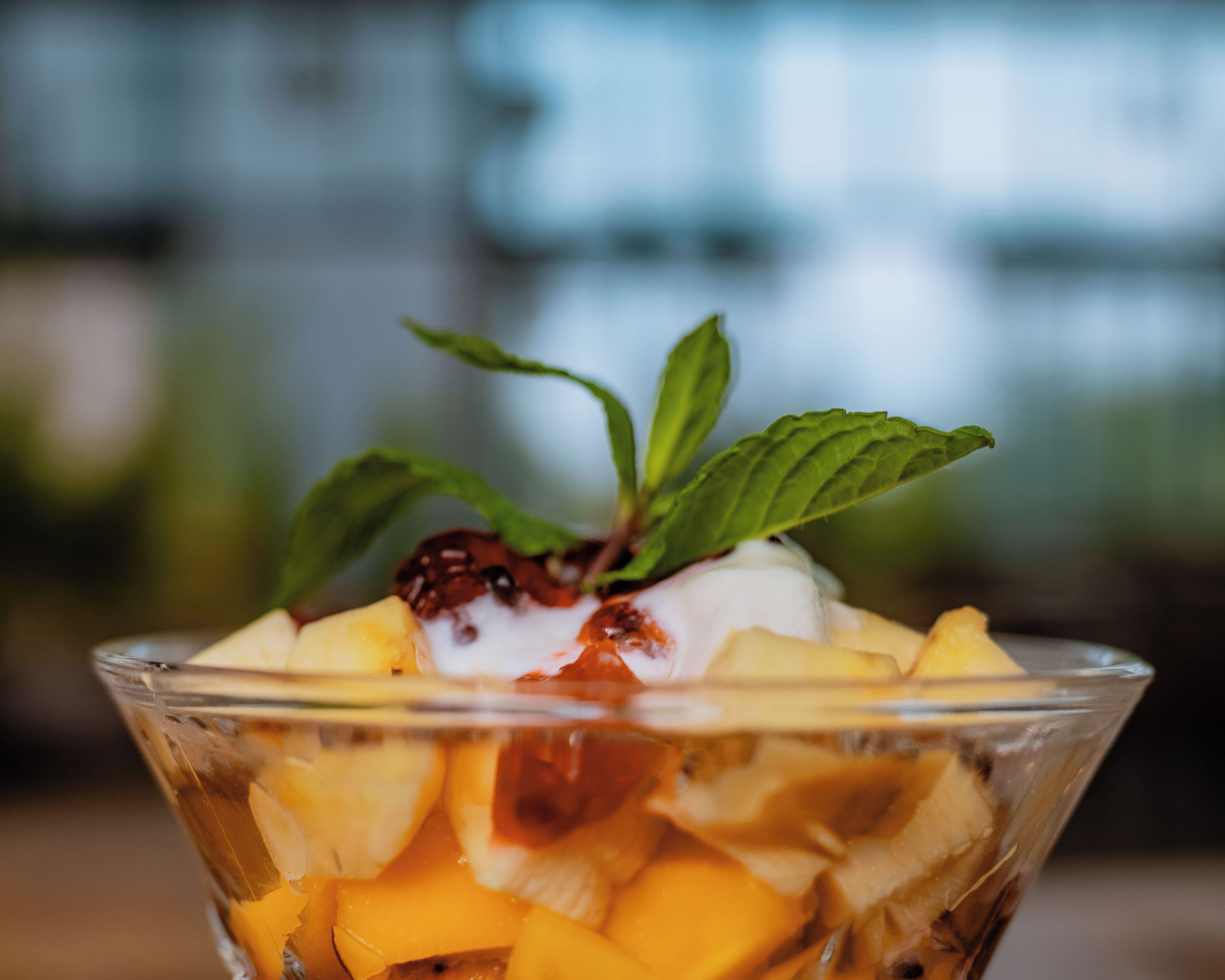 Eine transparente Schale mit einer geschichteten Nachspeise, Obst und einem Klecks Sahne.