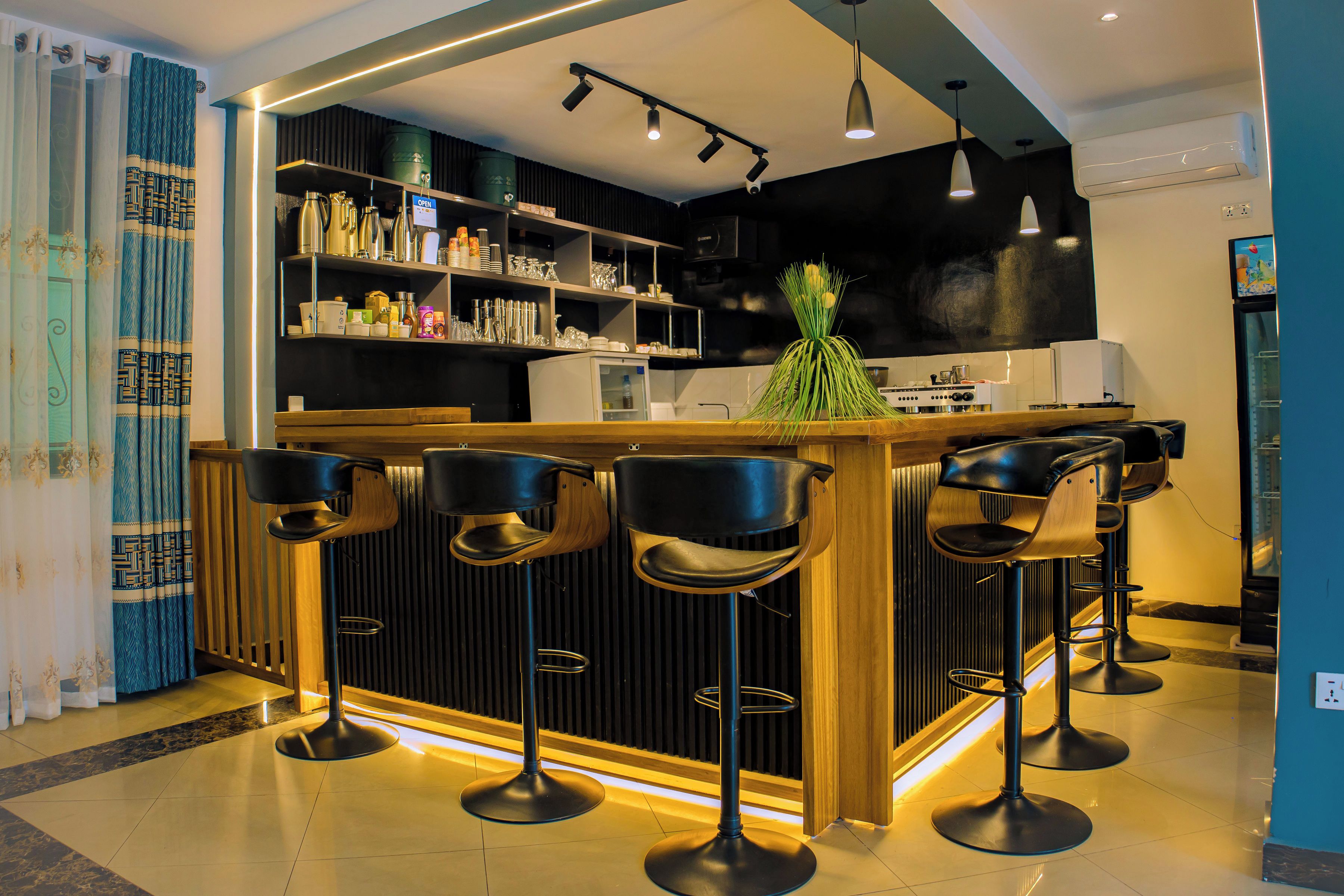A modern kitchen with a bar area, equipped with stools and overhead lighting.