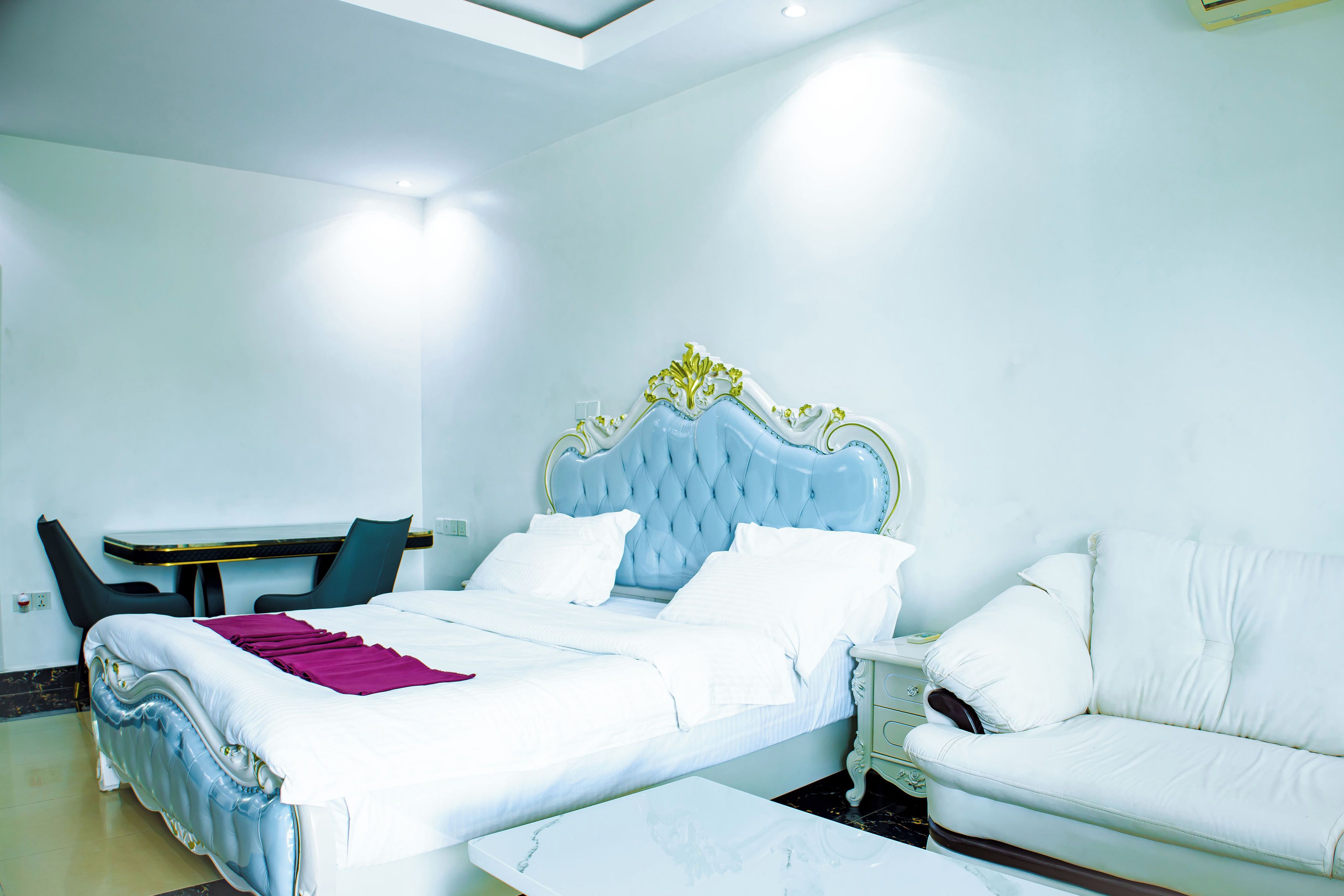 A hotel room with a bed, a sofa, a small table, and a chair.