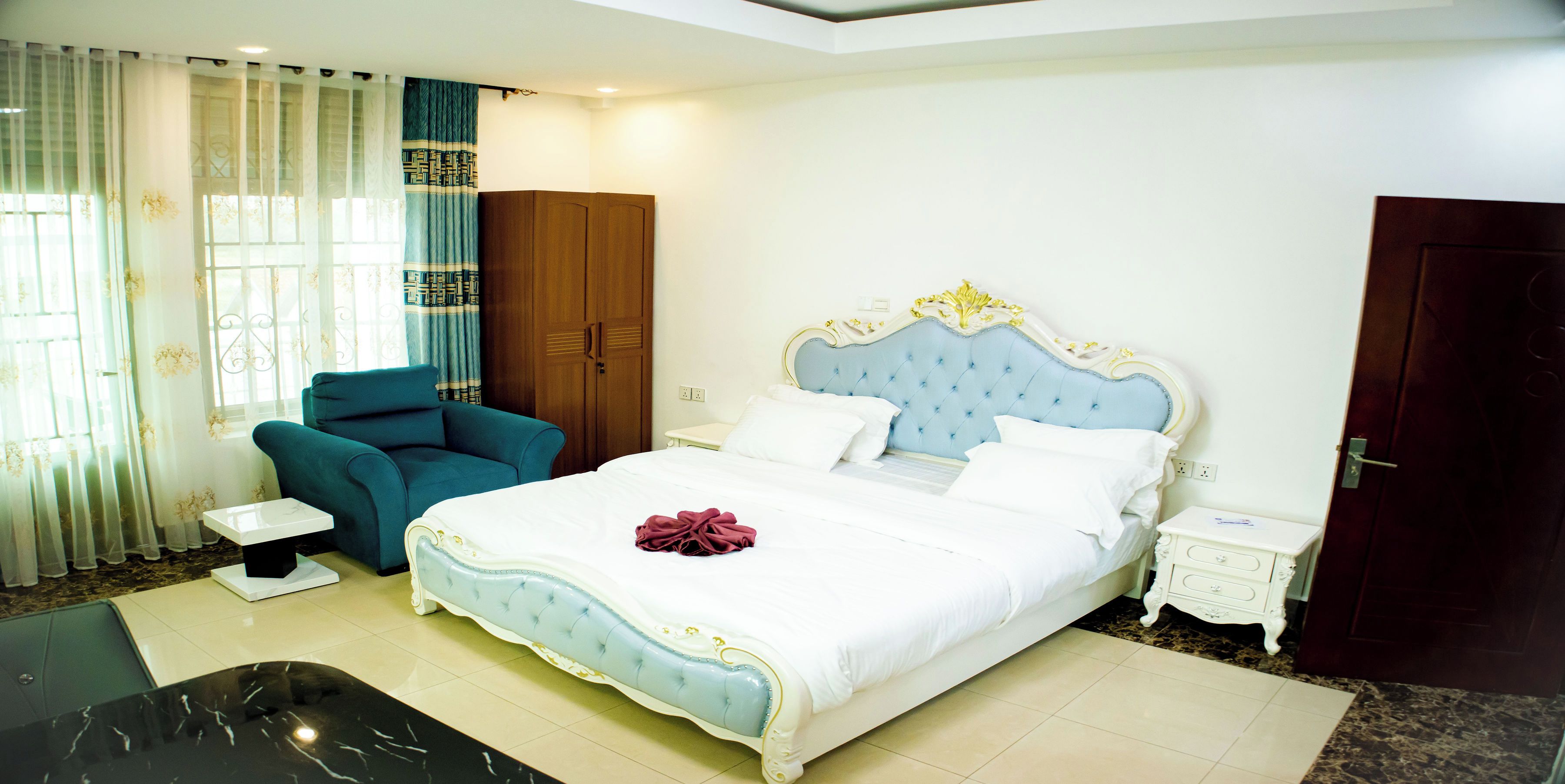 A bedroom with a bed, a chair, a wardrobe, and a nightstand.