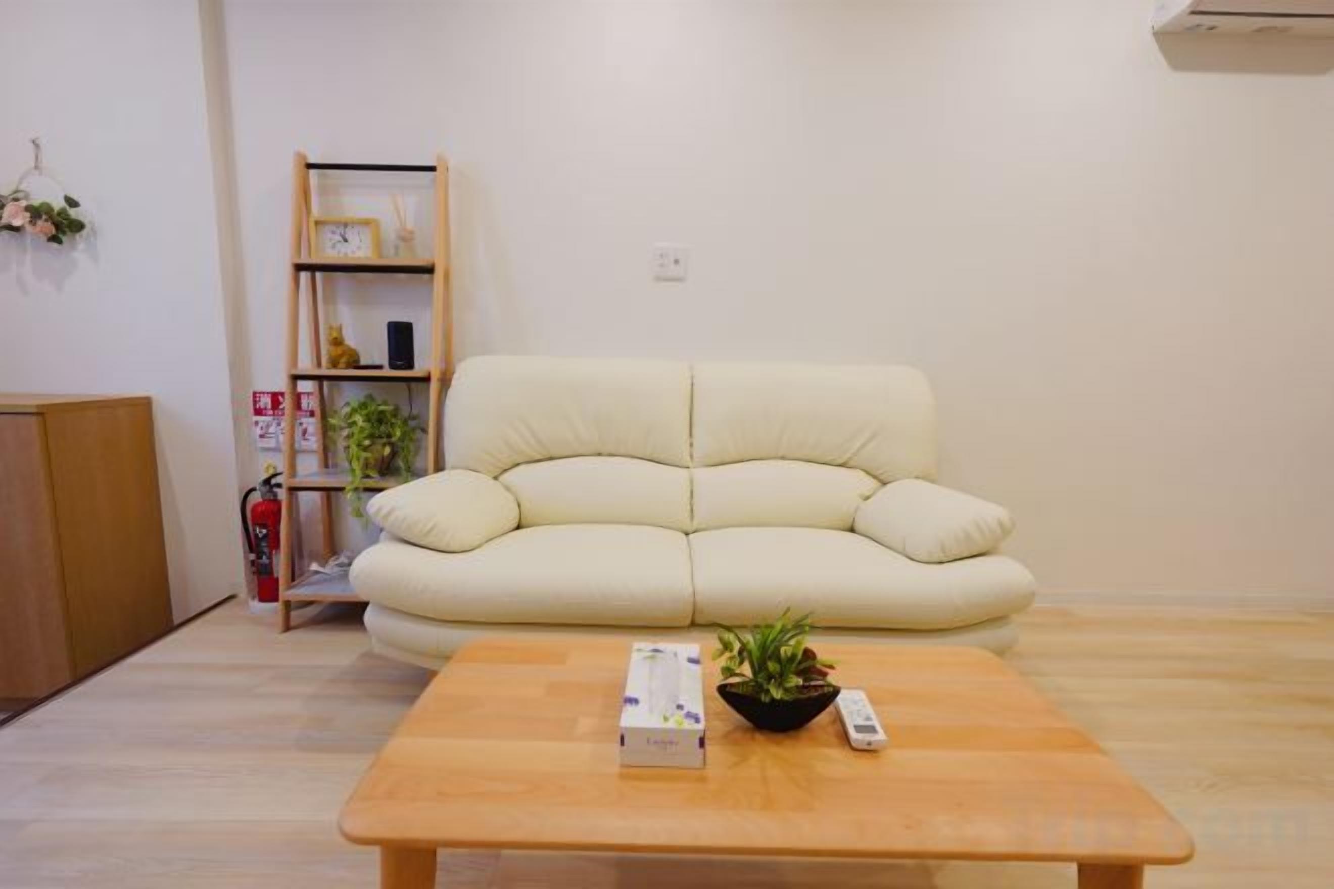 A living room with a beige sofa, a wooden coffee table, and a bookshelf.