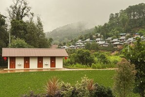 A building with a flat roof, multiple doors, and a paved area in front. - Baan Daeng Resort (Mae Hong Son)