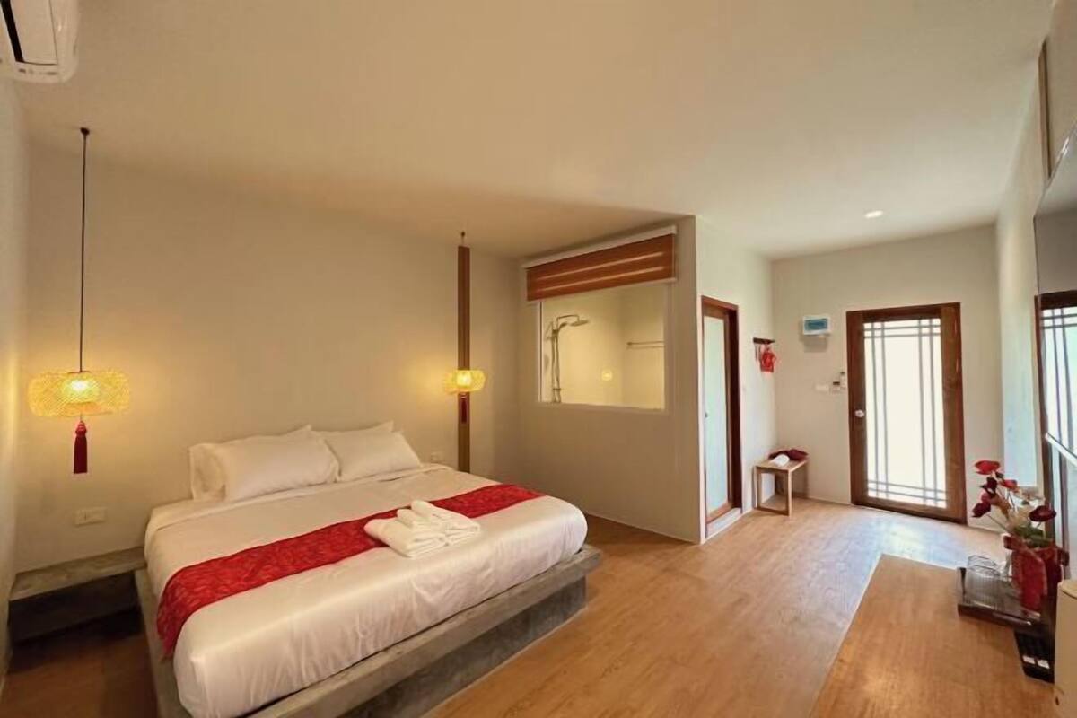 Habitació d'hotel amb llit, taulells laterals, un mirall, una porta i una taula petita.