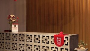 A reception desk with a decorative vase of flowers, a calendar, and a red sign.