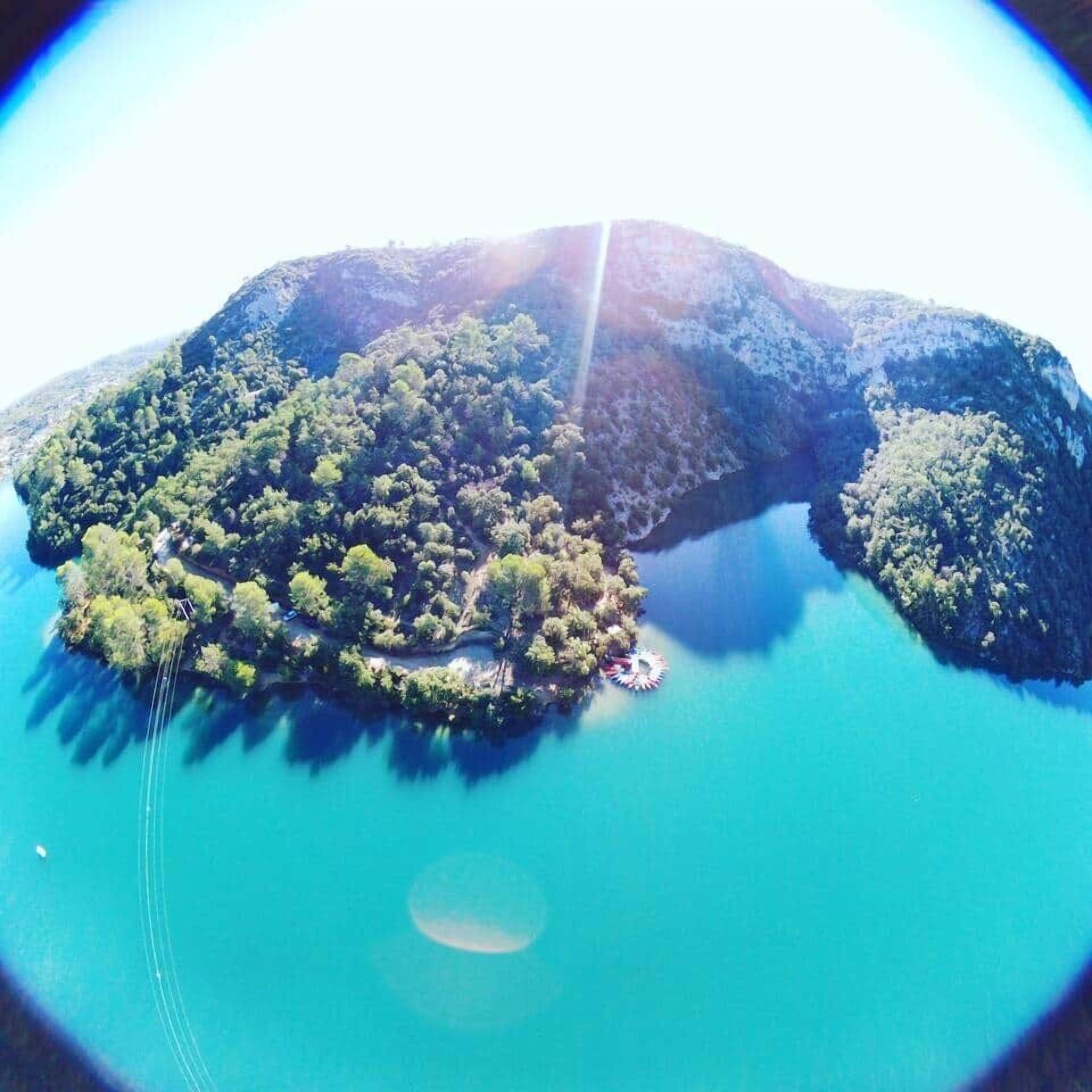 Vista aérea de una isla exuberante y verde rodeada de aguas azules y cristalinas.