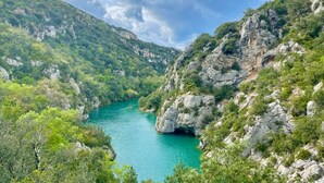 Un paisaje montañoso con un río turquesa, acantilados rocosos y vegetación densa.