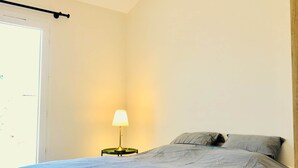 Un dormitorio con cama, lámpara de noche y lámpara colgante.