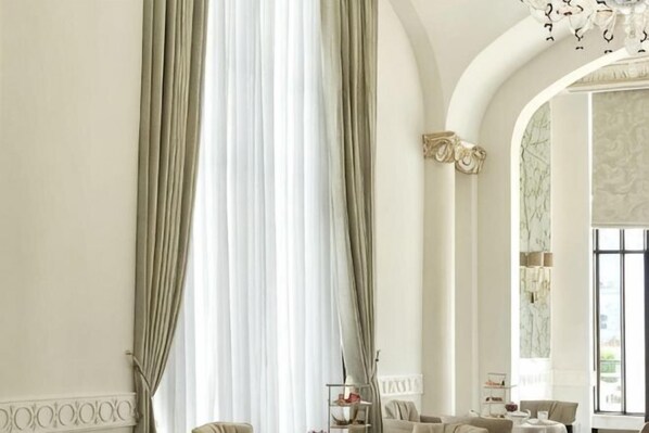 A room with a large window, a chandelier, and a high arched ceiling.
