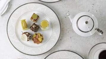 A table with a plate of assorted pastries and a teapot.