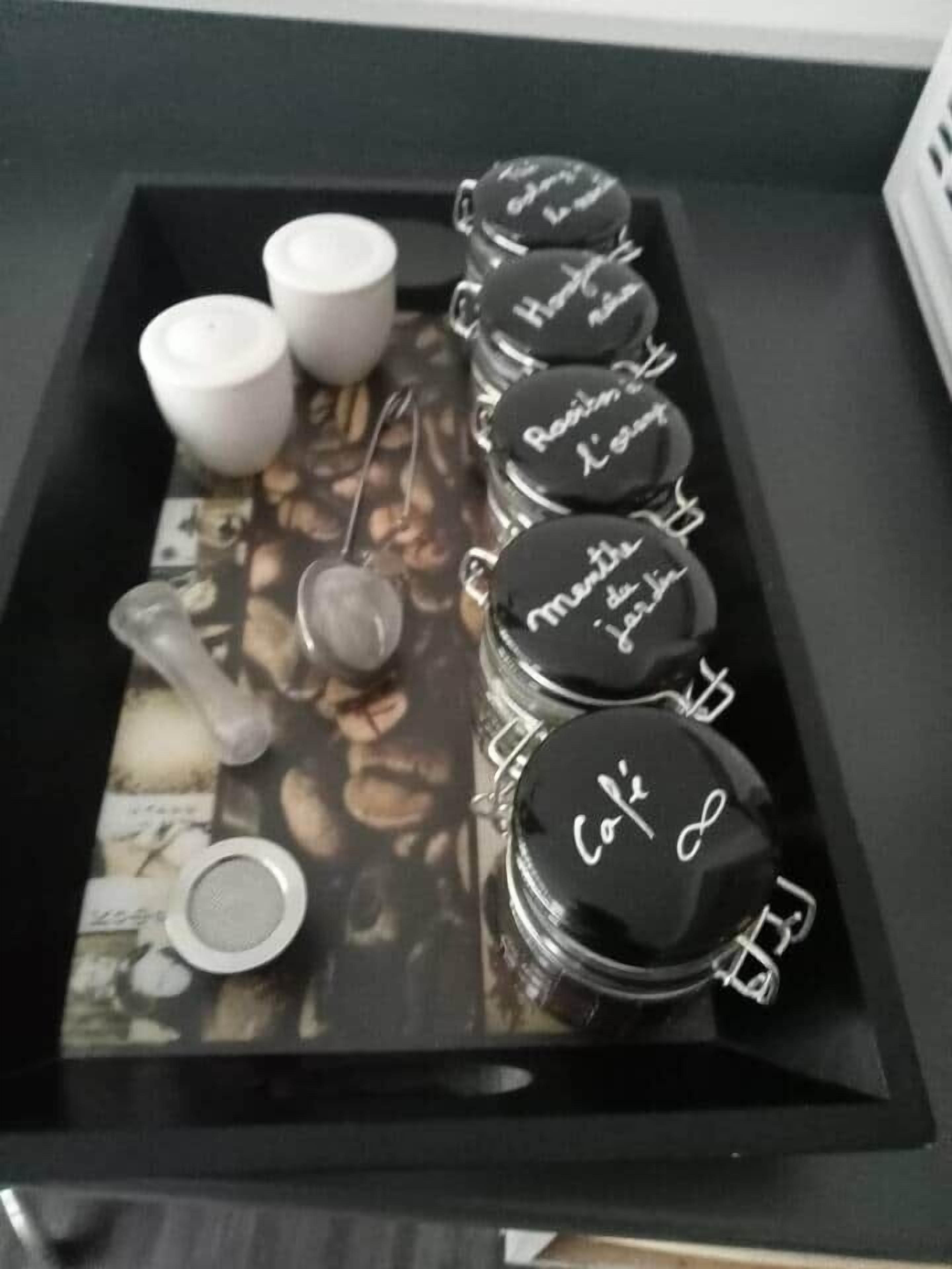 A tray with jars labeled with coffee-related terms, a spoon, and a small container.