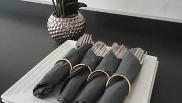 A neatly folded set of black napkins with gold rings on a white napkin holder on a black table.