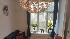 Un salon chaleureux avec un canapé noir, une petite table ronde et un luminaire décoratif au plafond.