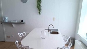 A modern dining area with a round table, four white chairs, a small potted plant, and a window. - Head in the clouds - Chez Anastasia (Charleroi)