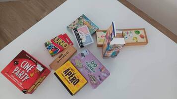 Una mesa blanca con varios juegos de mesa y una caja roja con el rótulo 'Cine Party'.
