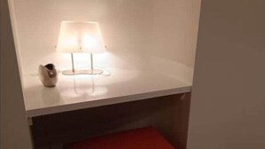 A room with a white wall, a red bench, and a lamp on a white surface. - Head in the clouds - Chez Anastasia (Charleroi)
