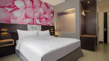 A modern hotel room with a large bed, a nightstand, a wall-mounted light, and a wardrobe with a mirror.