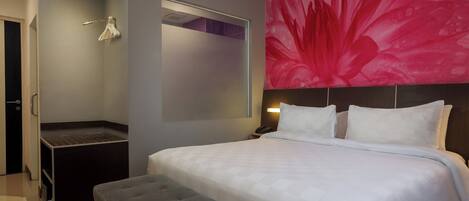 Ein modernes Hotelzimmer mit einem großen Bett, einer grauen Bank, einer Duschkabine und einem lebhaften Blumenbild an der Wand.