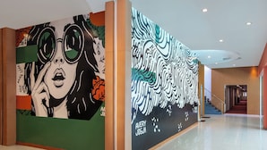 Eine moderne Lobby mit einer großen Wandmalerei, einer Treppe und einem sauberen, gefliesten Boden.