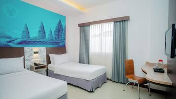 A hotel room with two beds, a desk, a chair, a TV, and a large wall mural.