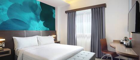 Una habitación de hotel moderna con una cama grande, un escritorio, una silla y un televisor.