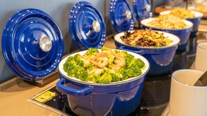 En buffet med forskellige retter i blå serveringsbeholdere.