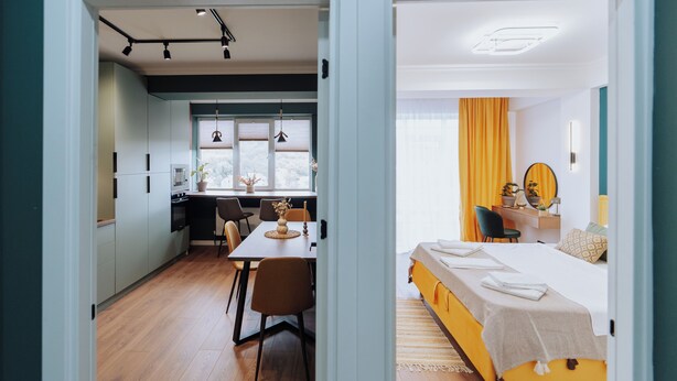 A modern hotel room with a bed, a desk, and a dining area. - Renovated 1BR • City View • Workspace (Chișinău)