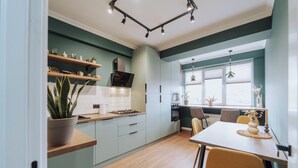 A modern kitchen with light blue cabinets, a wooden countertop, and a dining area with a table and chairs. - Renovated 1BR • City View • Workspace (Chișinău)