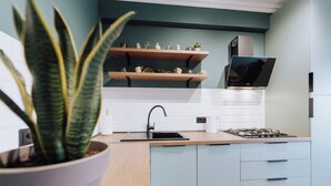 A modern kitchen with light blue cabinets, a wooden countertop, a sink, and a stove. - Renovated 1BR • City View • Workspace (Chișinău)