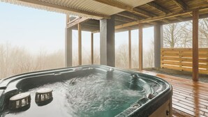 A hot tub under a wooden deck with a view of bare trees. - Luxury VIEWS from 4700', Hot Tub, Modern Rustic (Seven Devils)