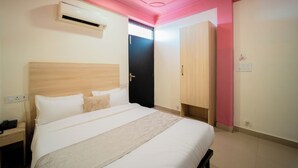 A hotel room with a bed, bedside table, and an air conditioning unit. - HOTEL CAPITOL SQUARE (Jaipur)